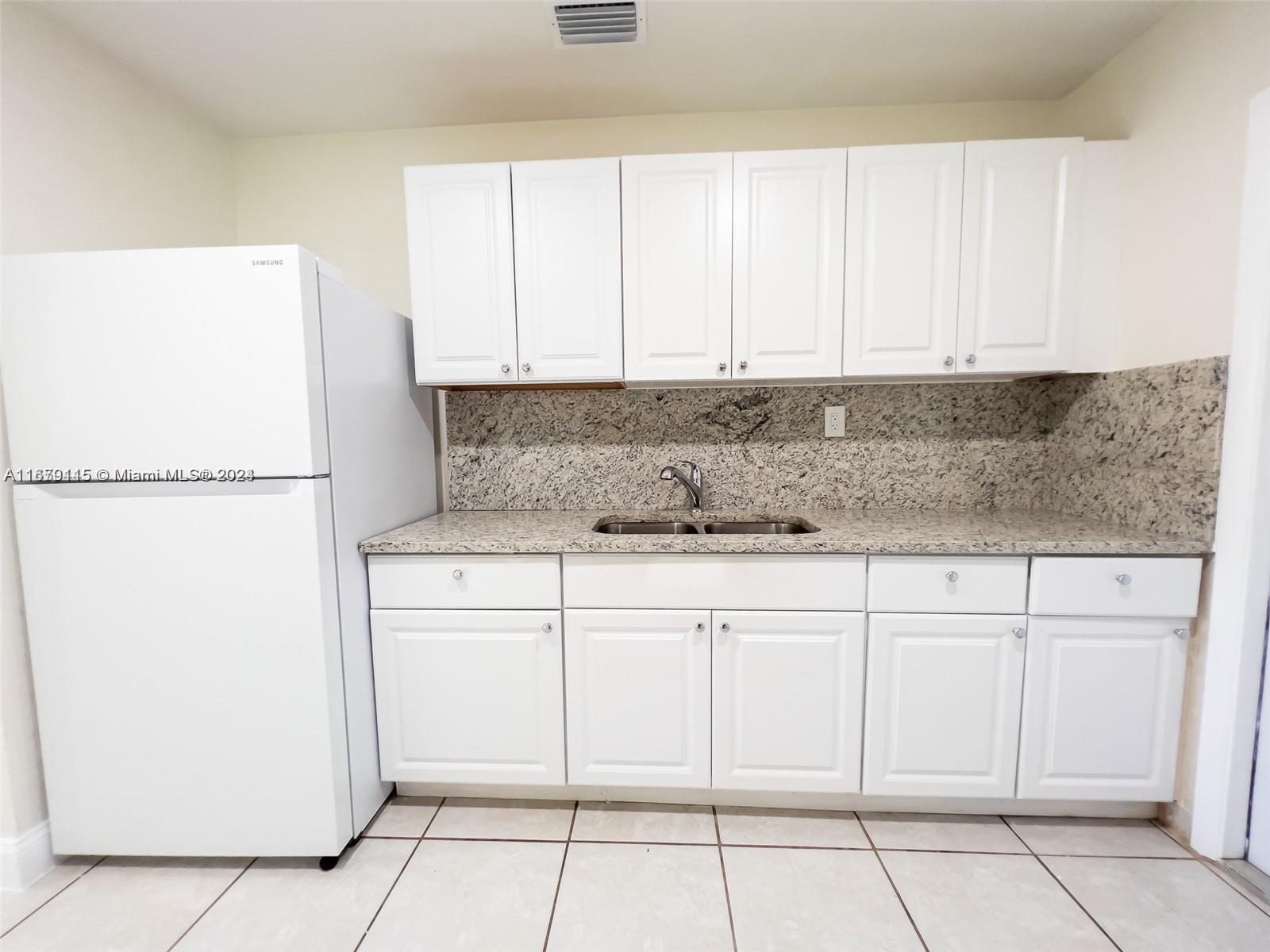 a kitchen with cabinets and a refrigerator