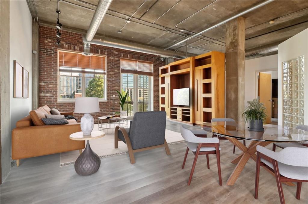 a living room with furniture two large windows and wooden floor