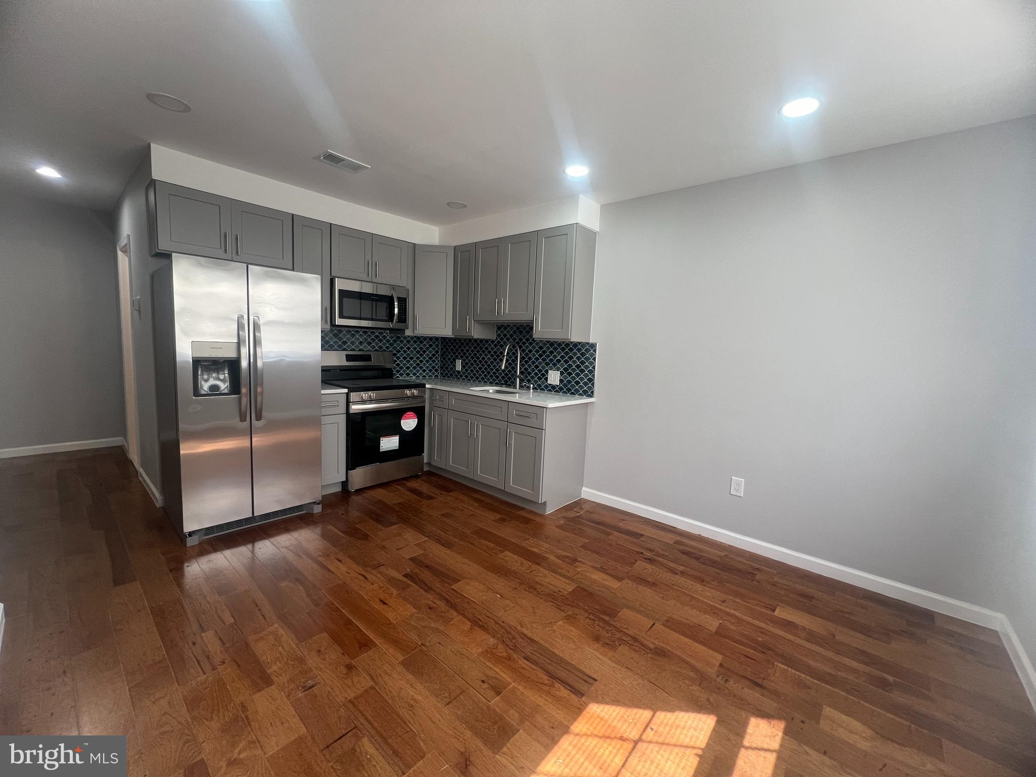 a kitchen with granite countertop a refrigerator and a stove top oven