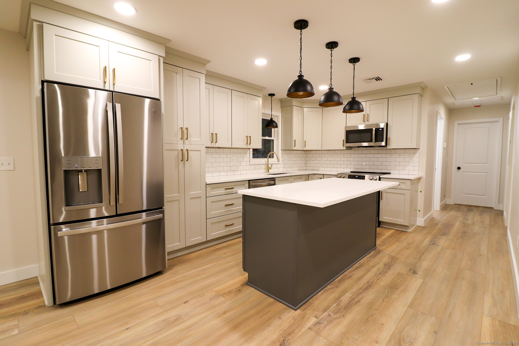 a kitchen with kitchen island a refrigerator stove and wooden floor