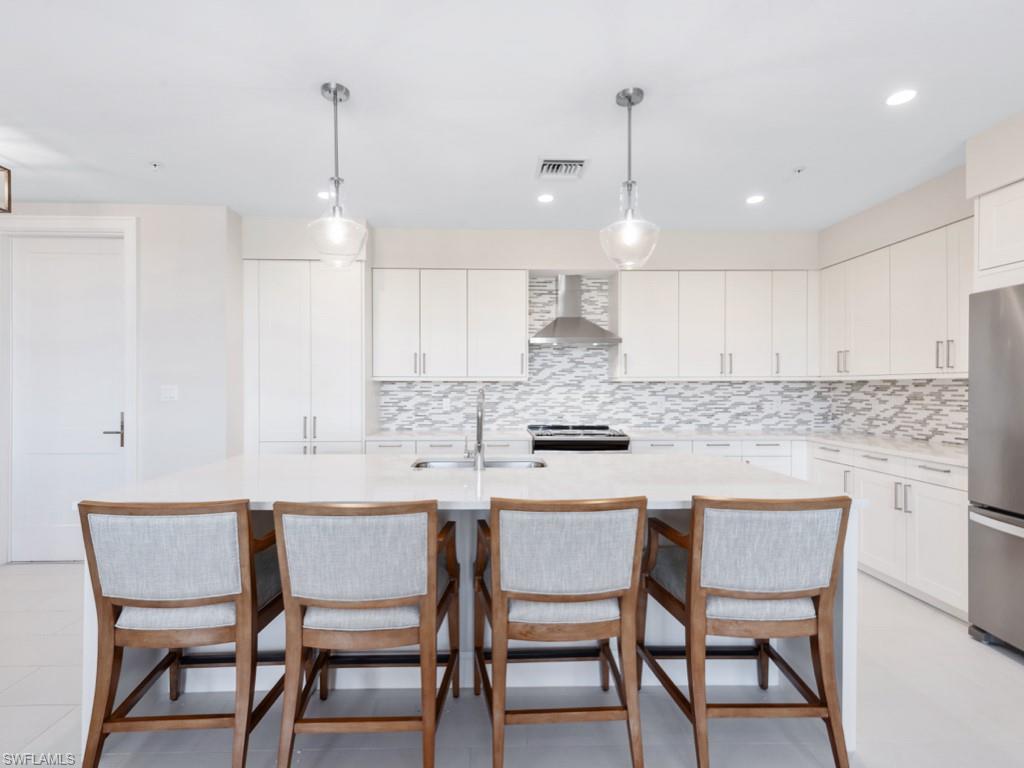 a kitchen with kitchen island a dining table chairs and white cabinets