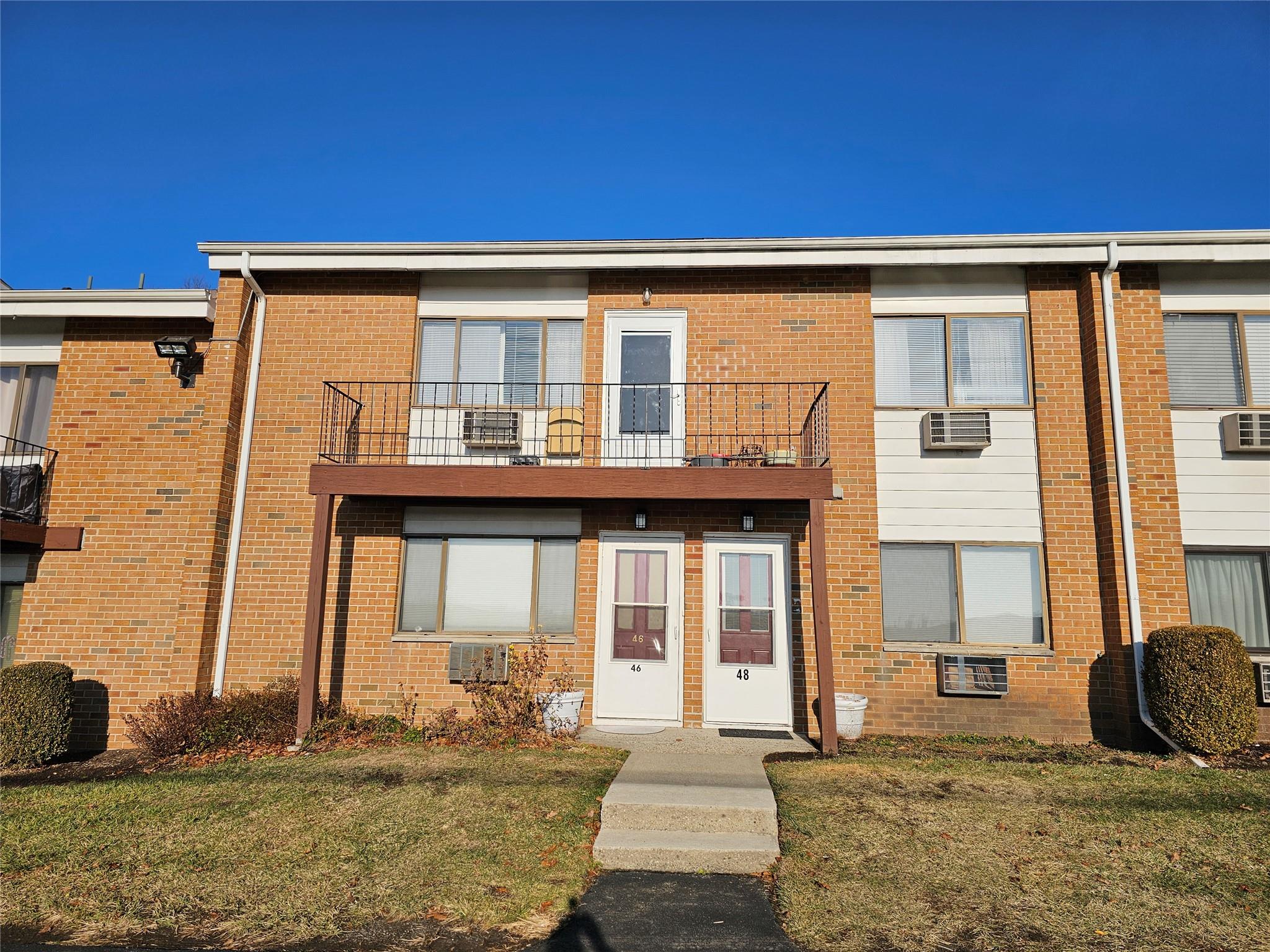 View of property with a balcony and a front lawn