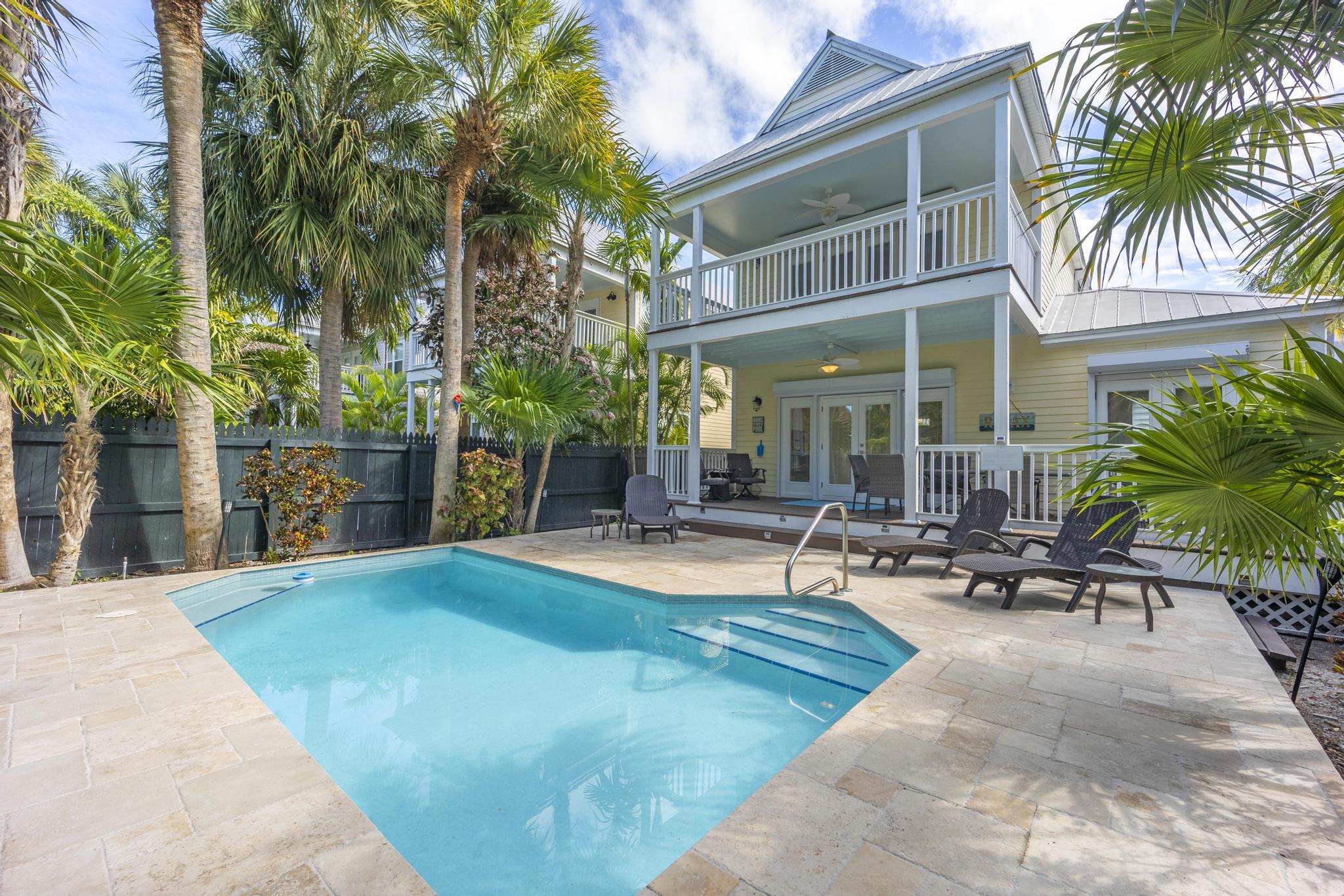 a view of a patio with a table and chairs under palm trees