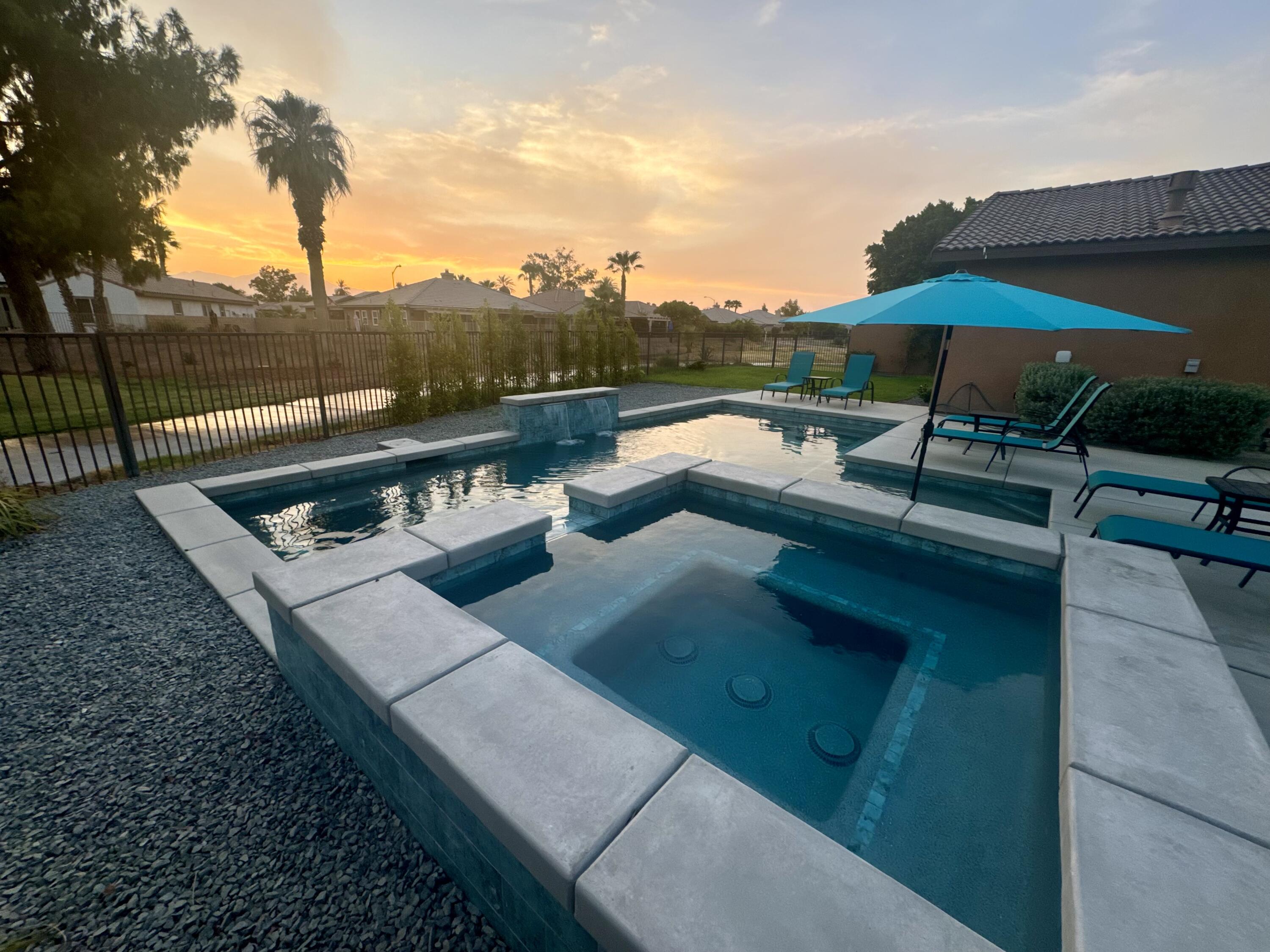 a view of a patio with couches table and chairs under an umbrella with a fire pit