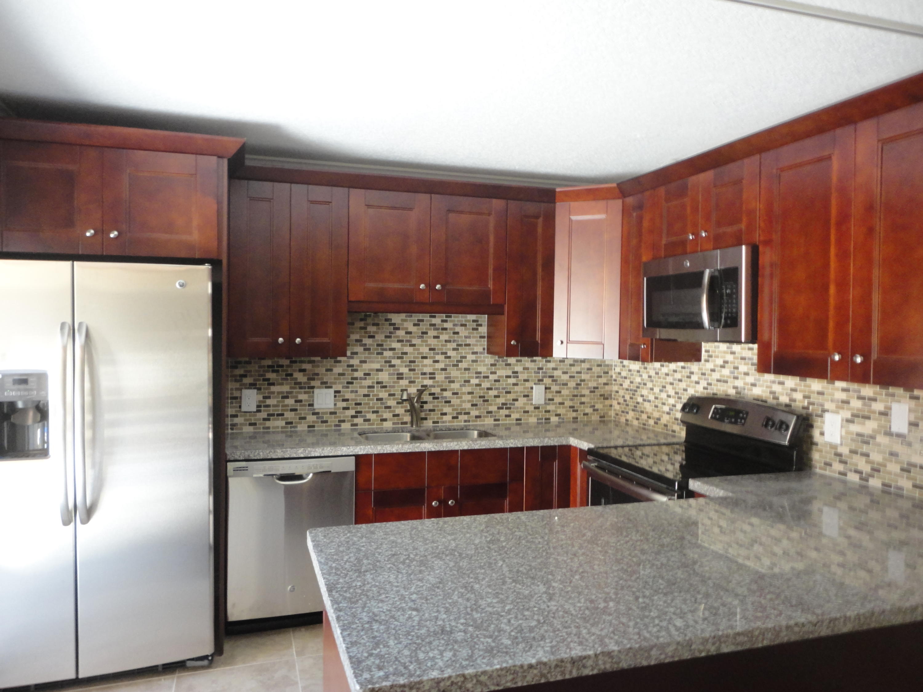 a kitchen with stainless steel appliances granite countertop a refrigerator a stove and a sink with wooden cabinets