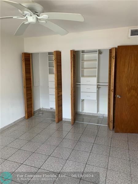 an empty room with closet and a ceiling fan