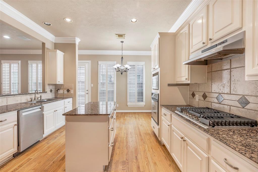 a large kitchen with stainless steel appliances granite countertop a lot of counter space and wooden floors