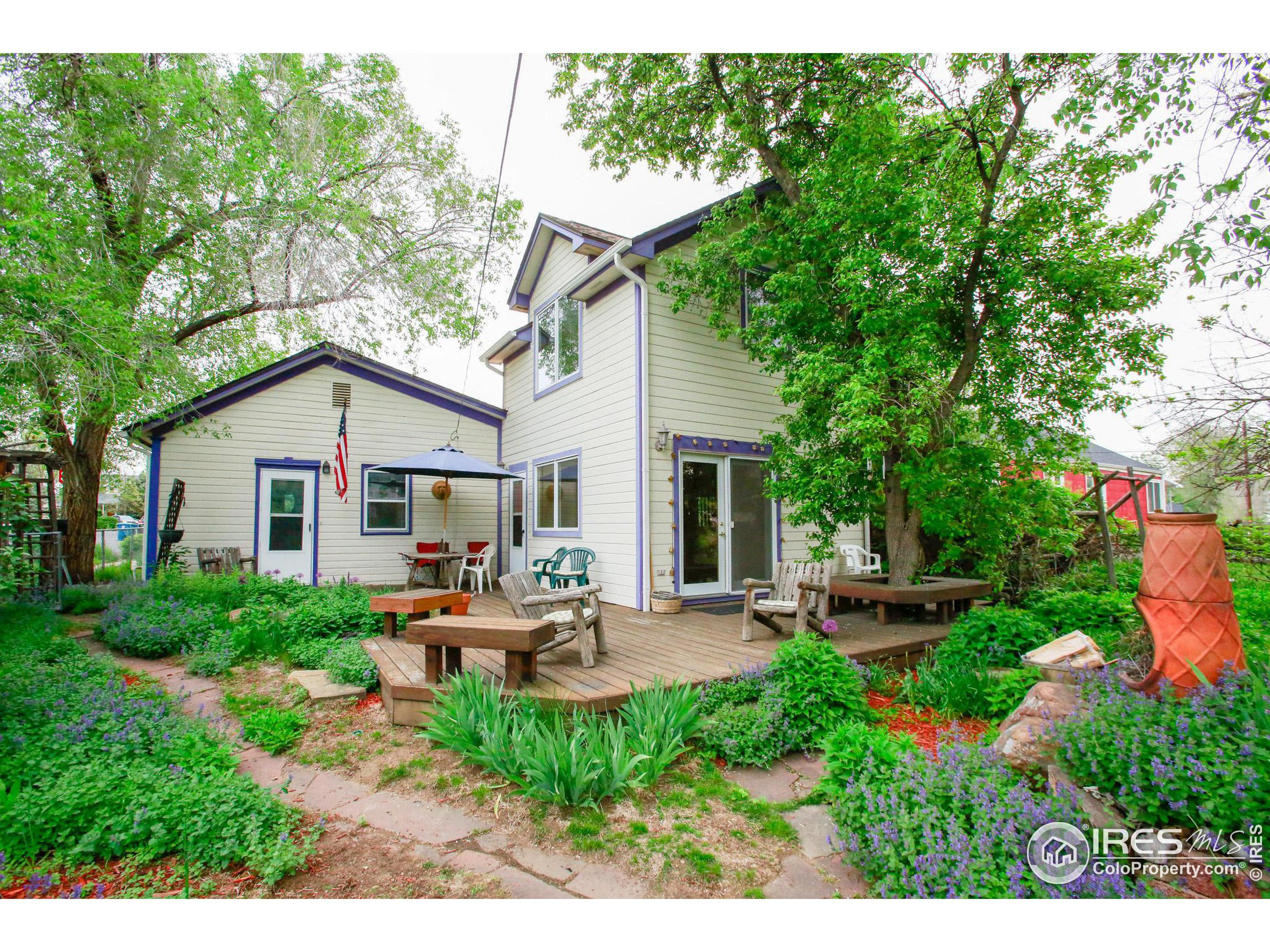 a view of backyard of house with outdoor seating and green bushes