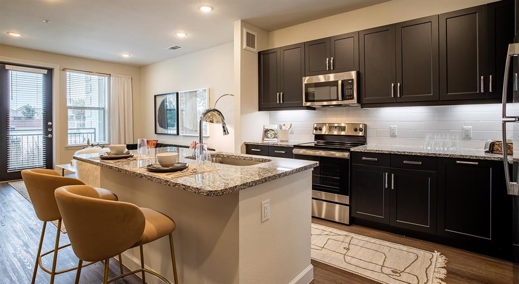 a kitchen with stainless steel appliances granite countertop a stove a sink and a microwave