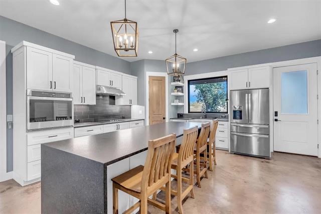 a kitchen with stainless steel appliances granite countertop a stove refrigerator and microwave