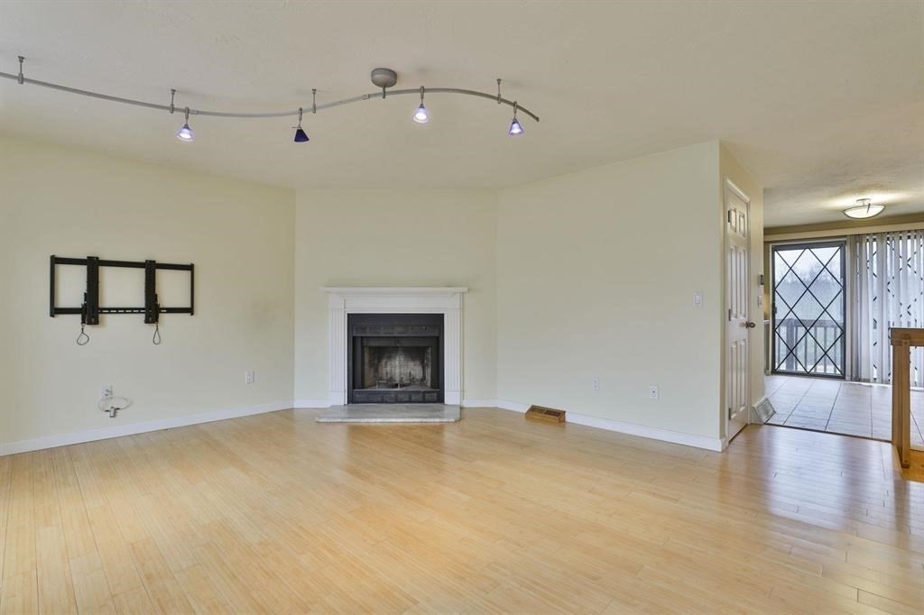 a view of an empty room with window and wooden floor