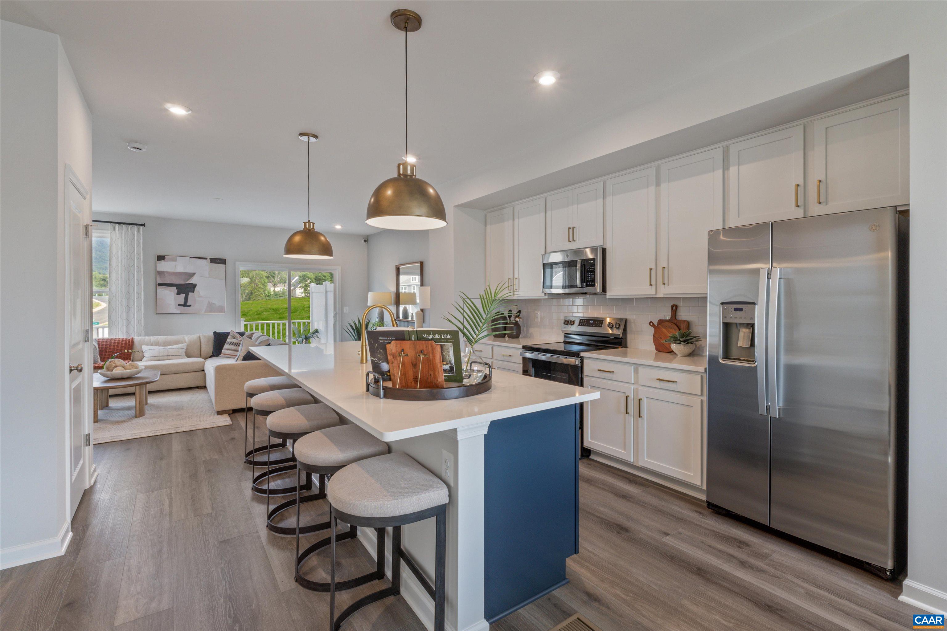 a kitchen with stainless steel appliances kitchen island granite countertop a refrigerator a stove a sink dishwasher a dining table and chairs with wooden floor