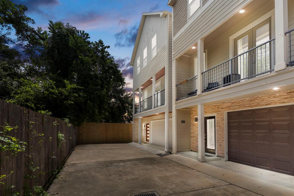 Contemporary multi-story single residence featuring a private garage, ample driveway parking, a balcony & a rooftop!. The home is complemented by exterior lighting and a fenced-in side and backyard.