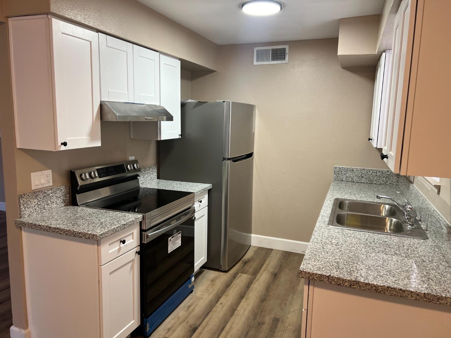 a kitchen with granite countertop a sink stove and refrigerator