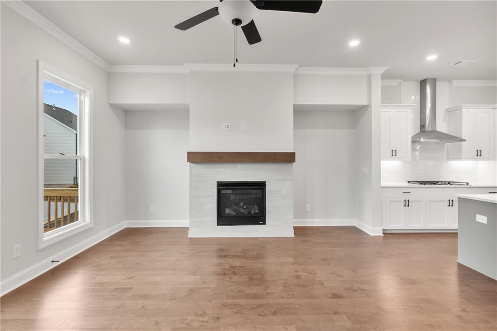 a view of an empty room and kitchen with fireplace wooden floor