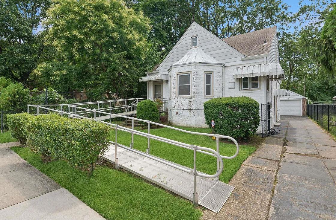 View of front of house with an outbuilding, a front yard, and a garage