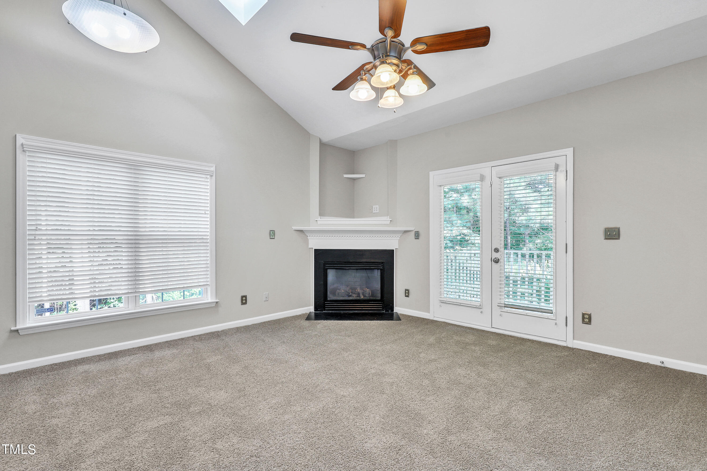 a view of an empty room with a fireplace and a window