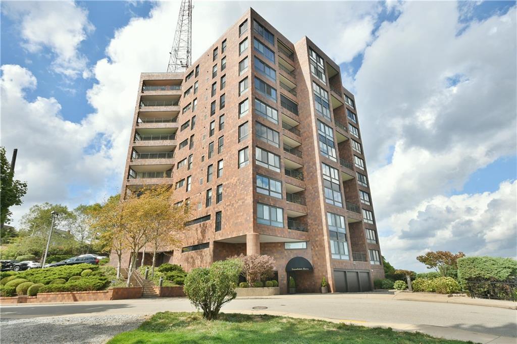 a front view of multi story residential apartment building with yard and parking space