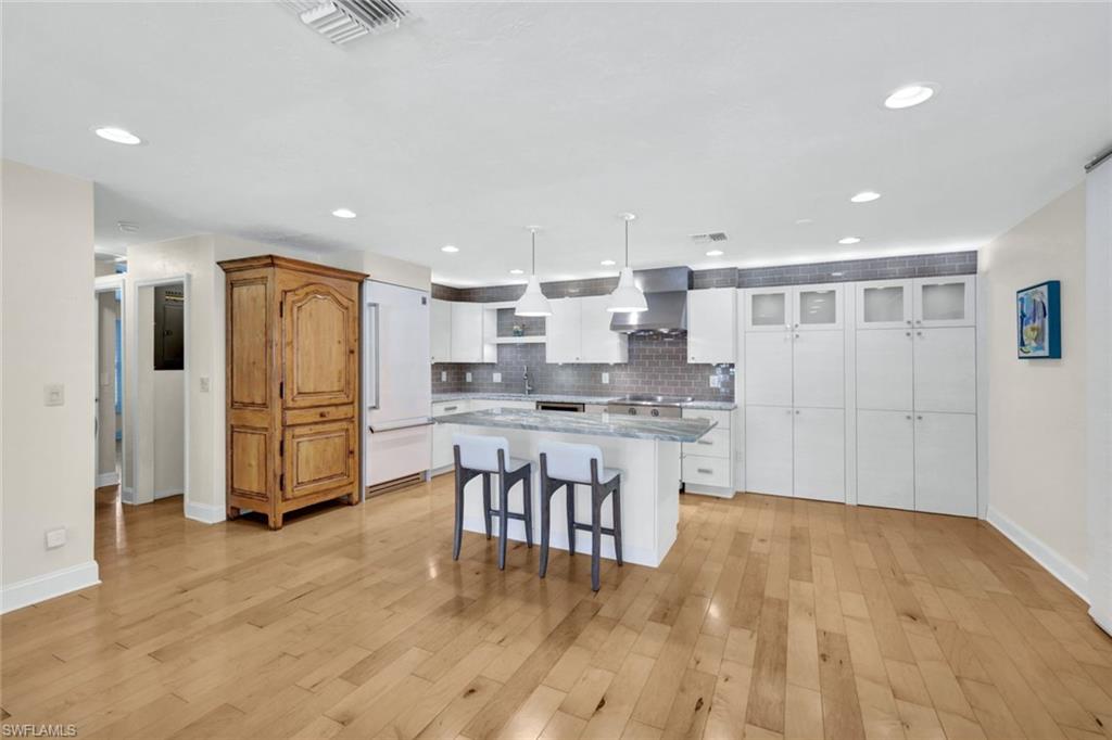 Designer kitchen with  custom cabinets, kitchen island with seating, a state of the art Induction range, electric oven, beautiful maple flooring, and room for your dining table.