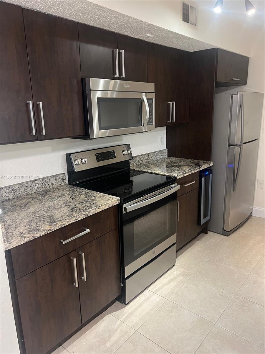 a kitchen with granite countertop a refrigerator and a stove