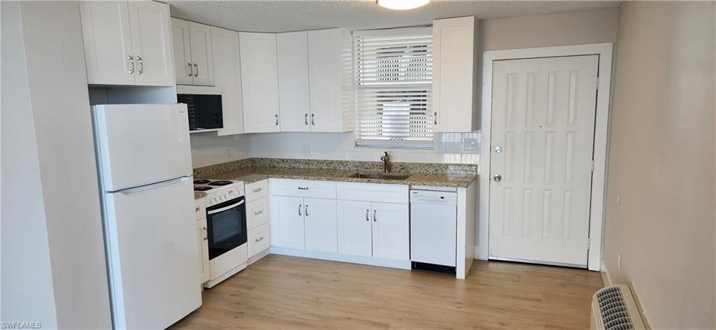 a kitchen with granite countertop white cabinets and white appliances