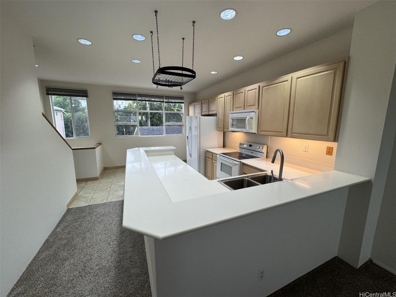 a kitchen with stainless steel appliances a sink a stove a refrigerator cabinets and a dining table with wooden floor