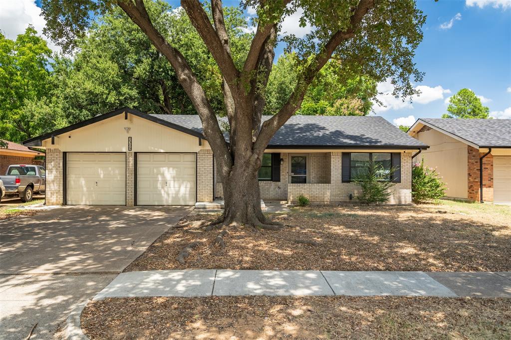 a view of a house with a yard and large tree