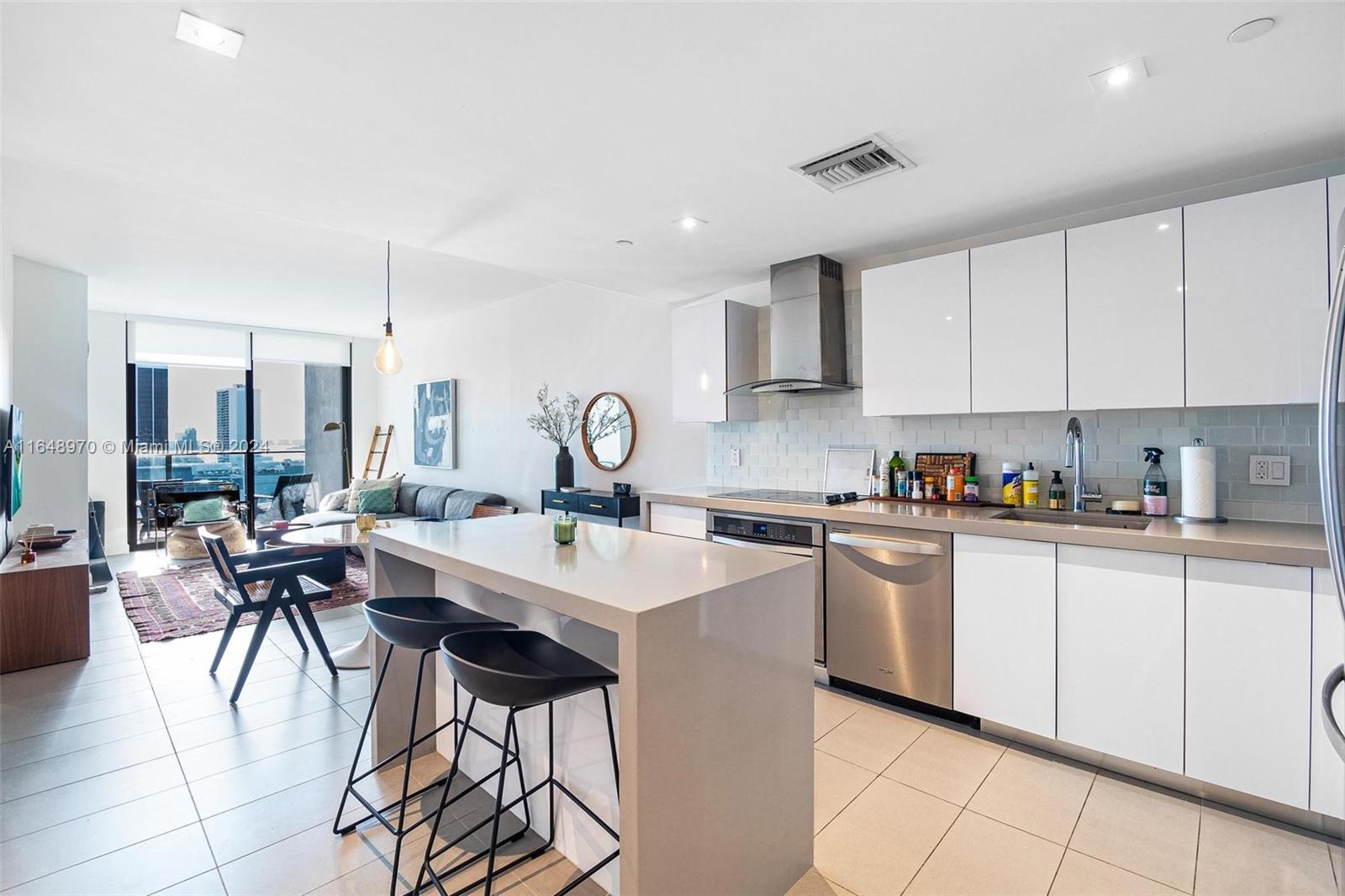 a kitchen with stainless steel appliances kitchen island a table chairs sink and cabinets