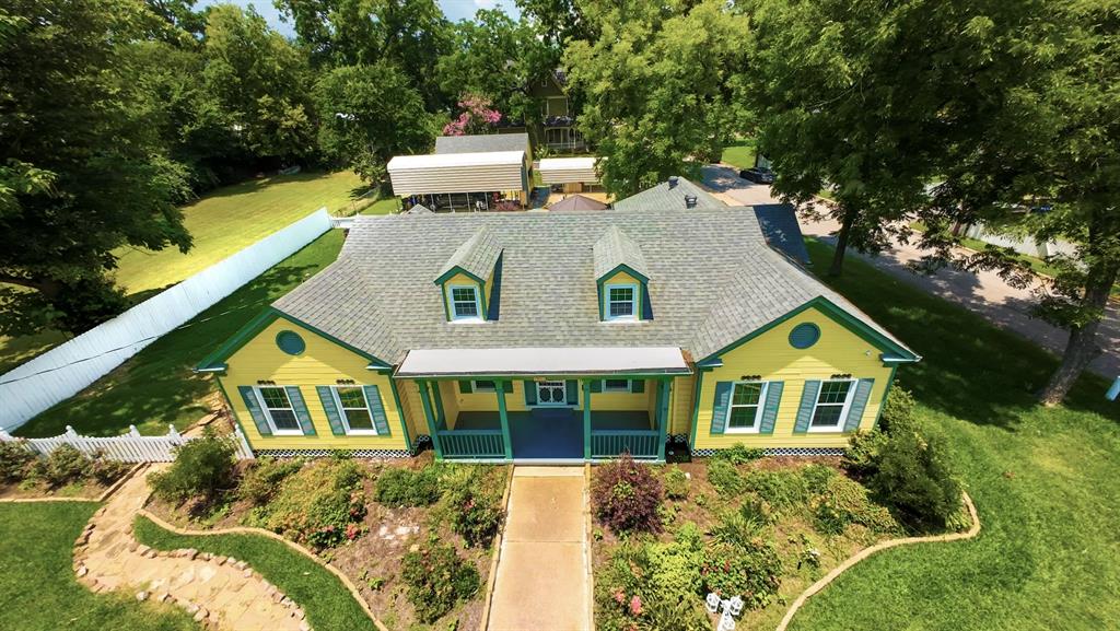 a aerial view of a house with a yard balcony and large trees