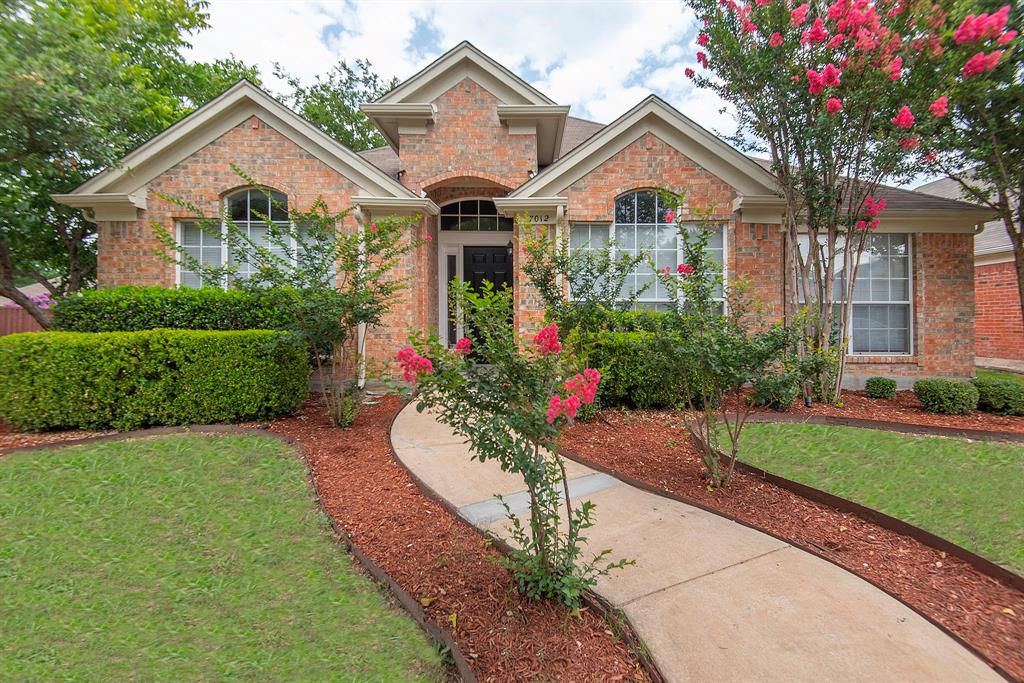 a front view of a house with a yard and potted plants