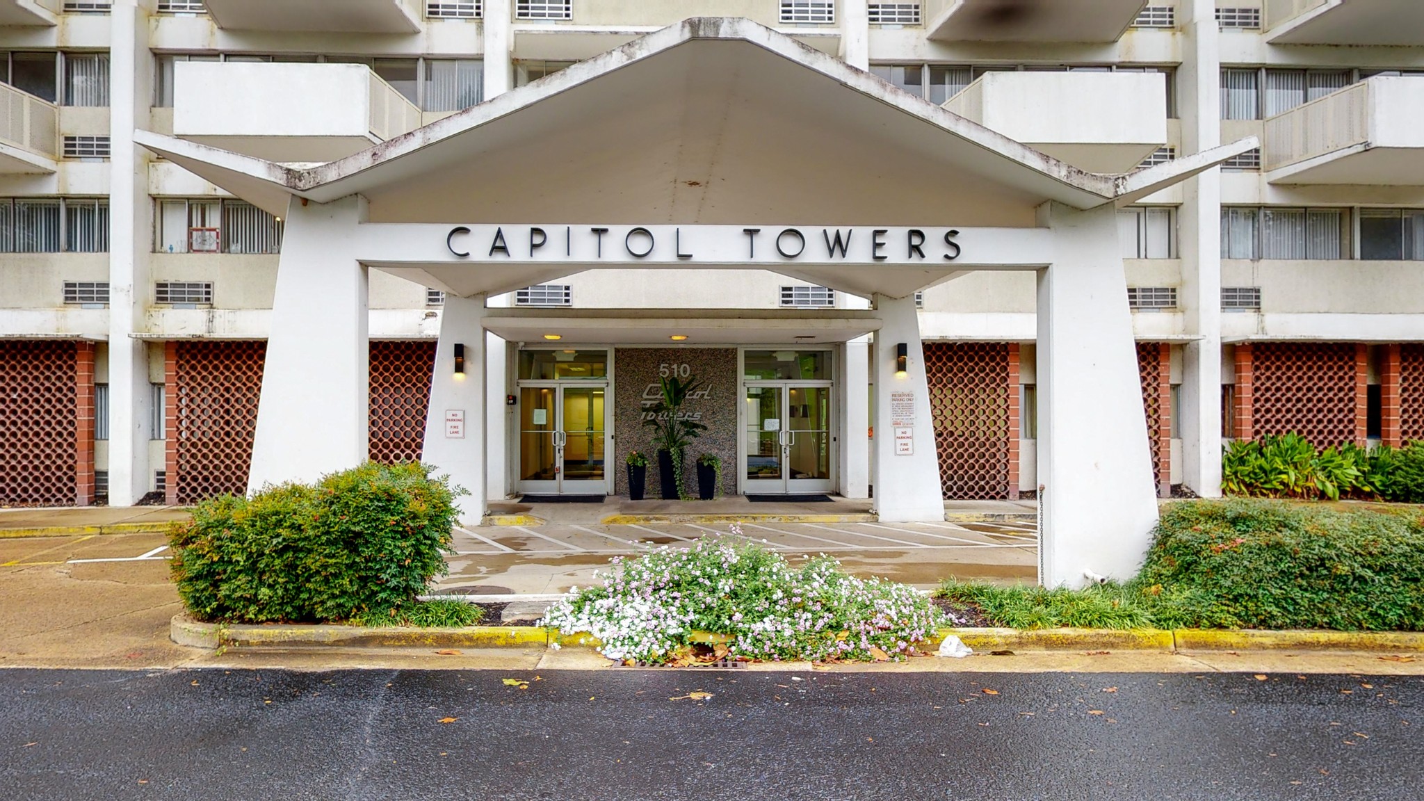 a front view of a building with a garden and plants