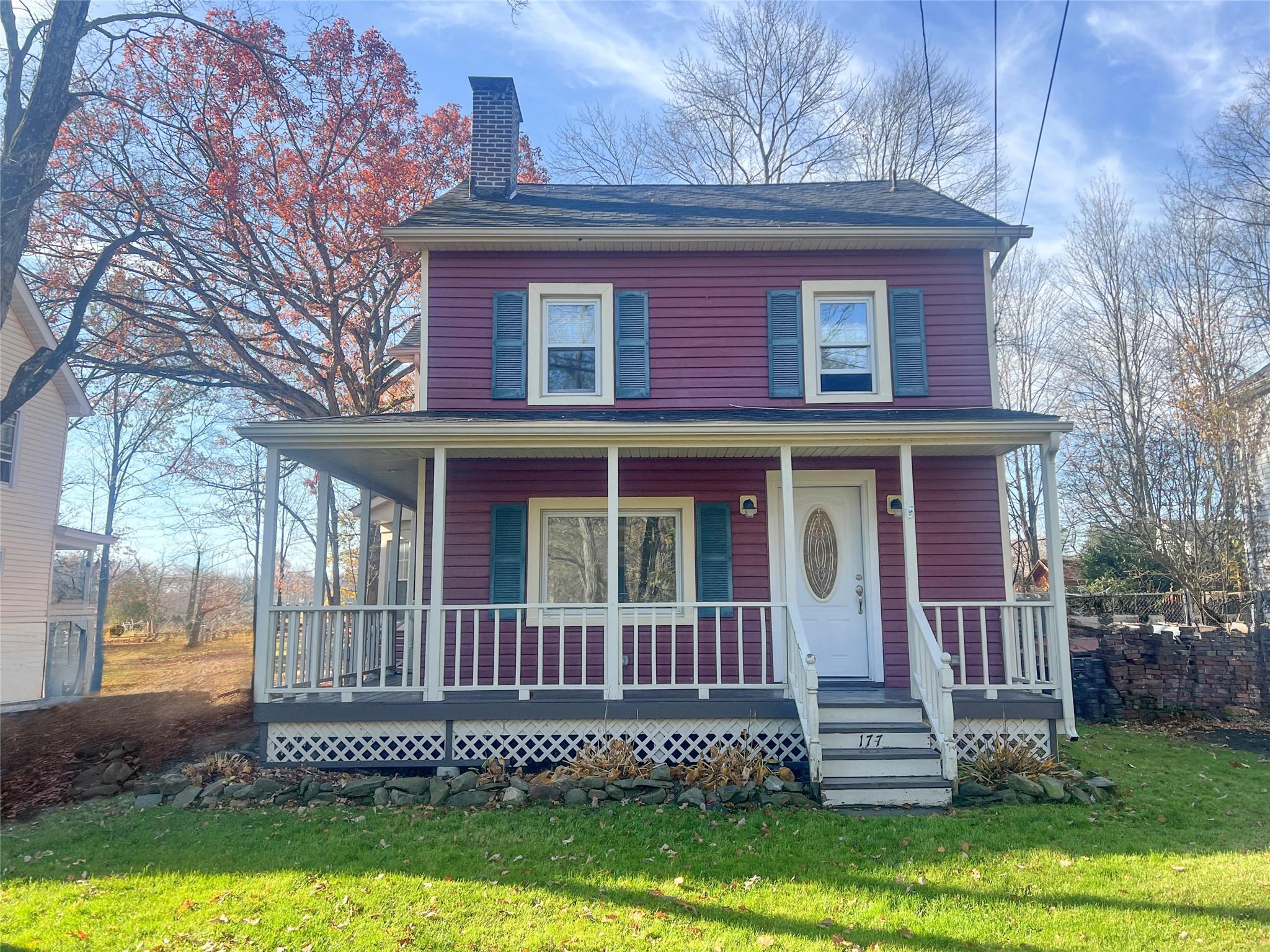 View of front facade featuring covered porch and a front yard