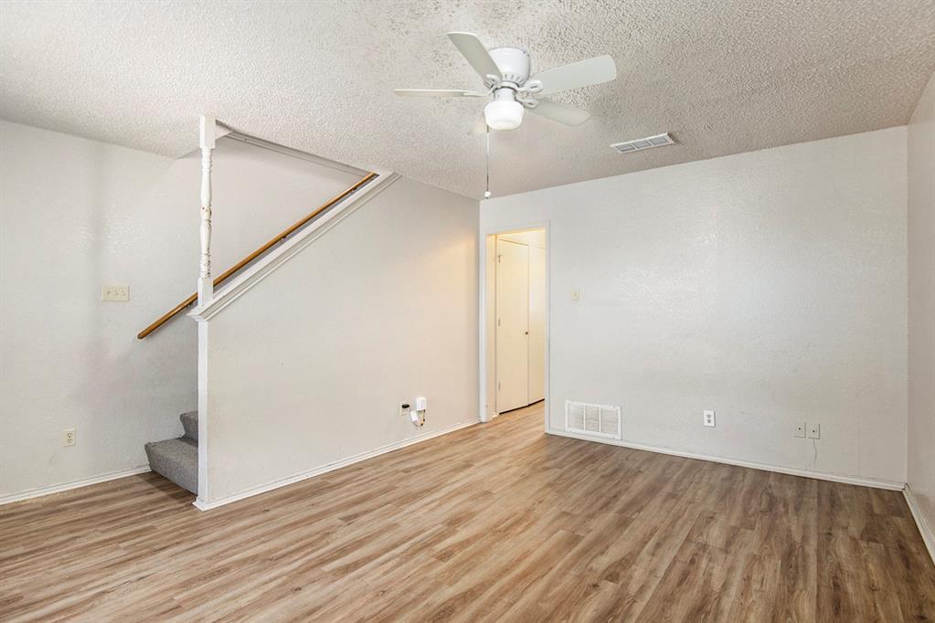 an empty room with wooden floor and ceiling fan