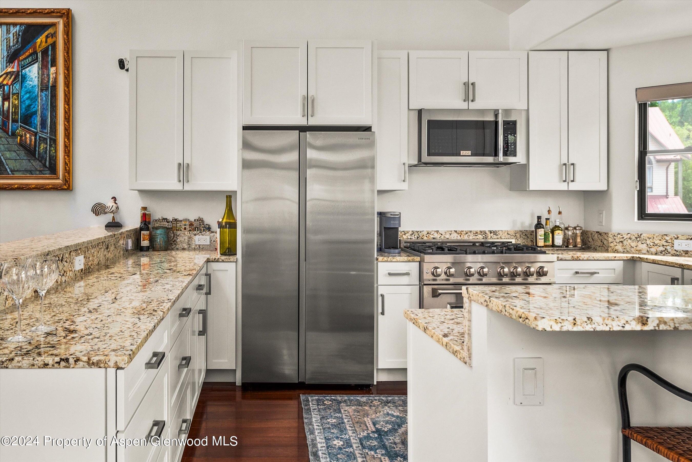 a kitchen with stainless steel appliances granite countertop a refrigerator a stove and a sink