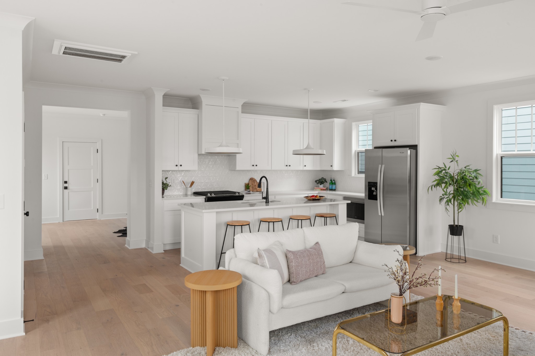 a living room with furniture a refrigerator and a white table with wooden floor