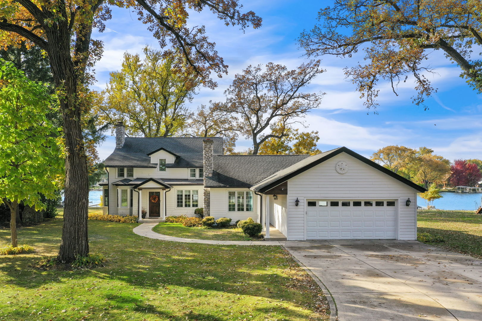 a view of white house with a big yard and large trees