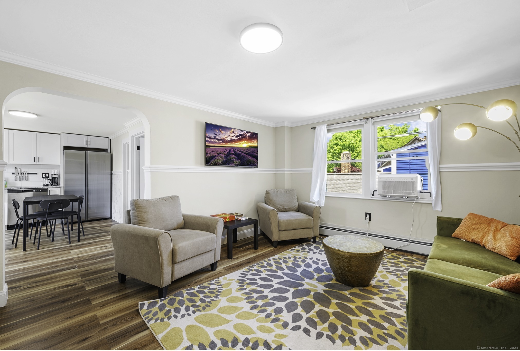 a living room with furniture two large window and a dining table