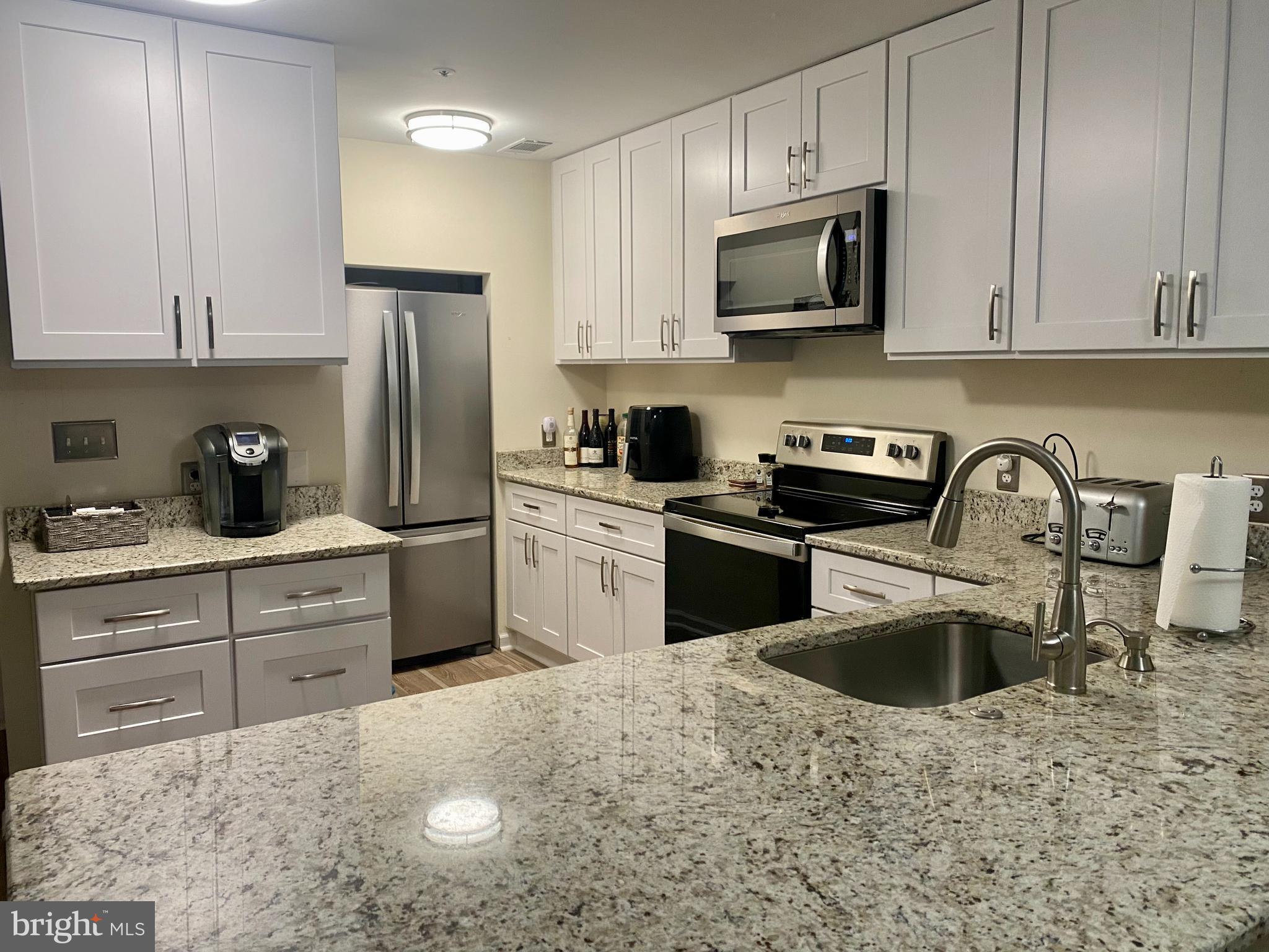 a kitchen with white cabinets sink and stainless steel appliances