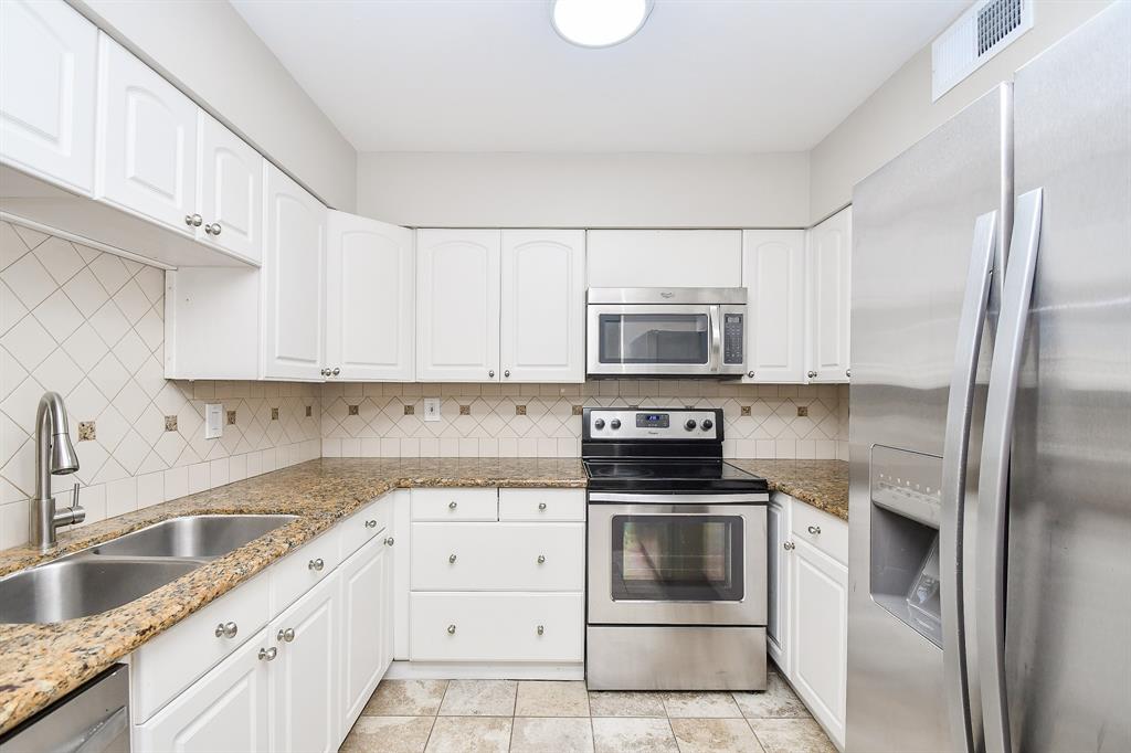 a kitchen with granite countertop white cabinets and stainless steel appliances