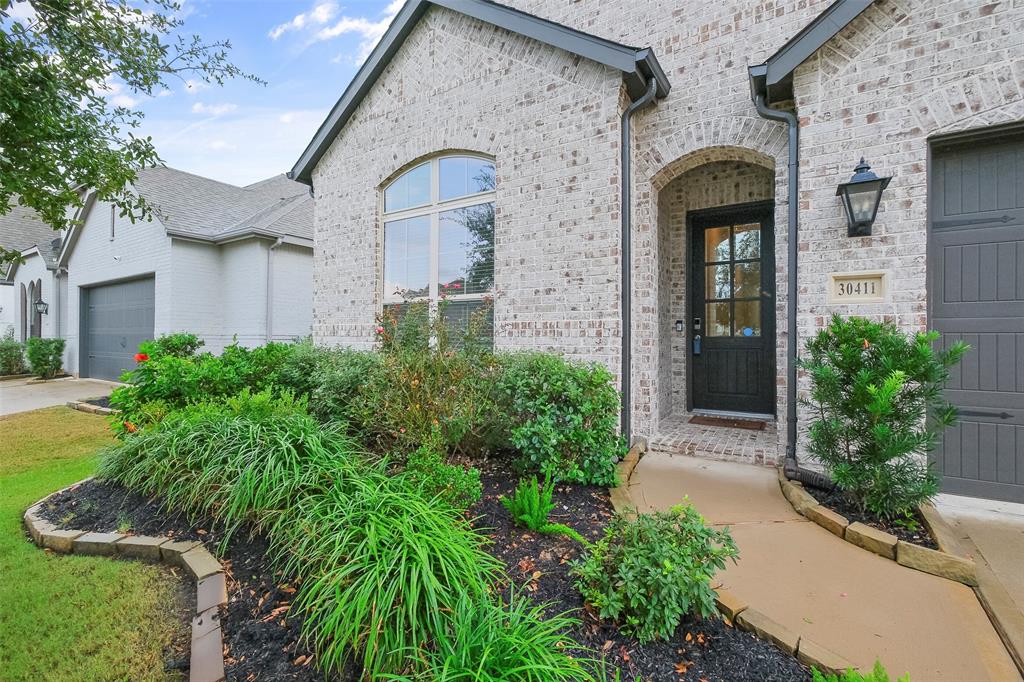 This is a charming single-story brick home featuring a large arched window, a covered entryway, and an attached garage. 