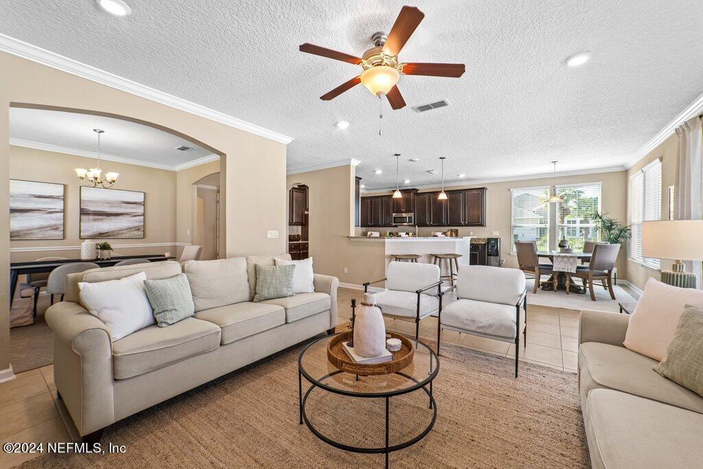 a living room with furniture kitchen view and a chandelier