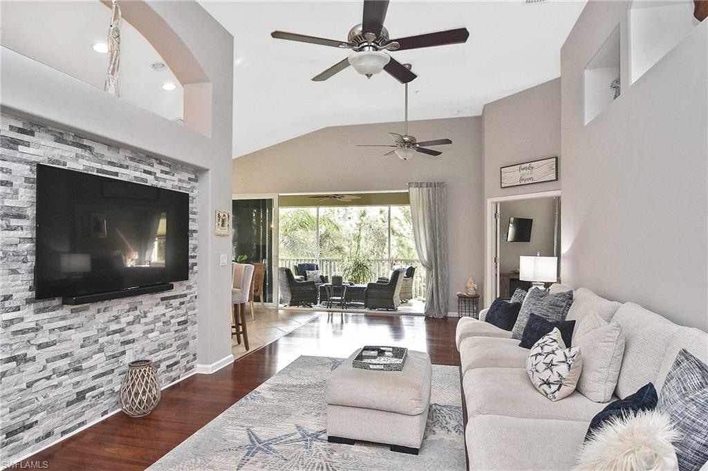 Living room with high vaulted ceiling, hardwood / wood-style flooring, and ceiling fan