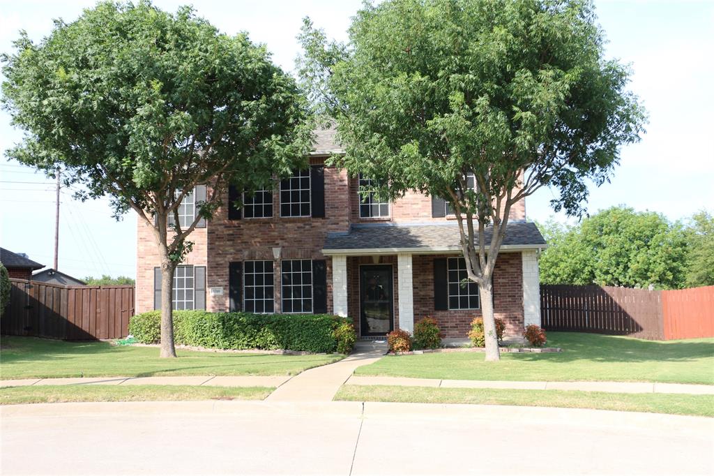 a front view of a house with a garden and trees