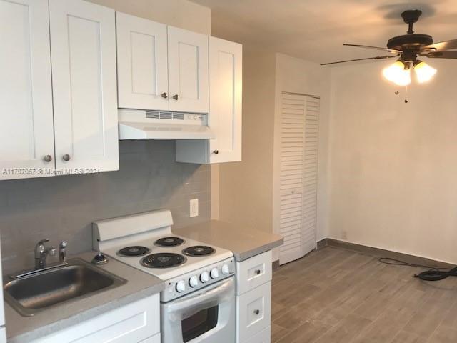 a kitchen with granite countertop white cabinets and white appliances