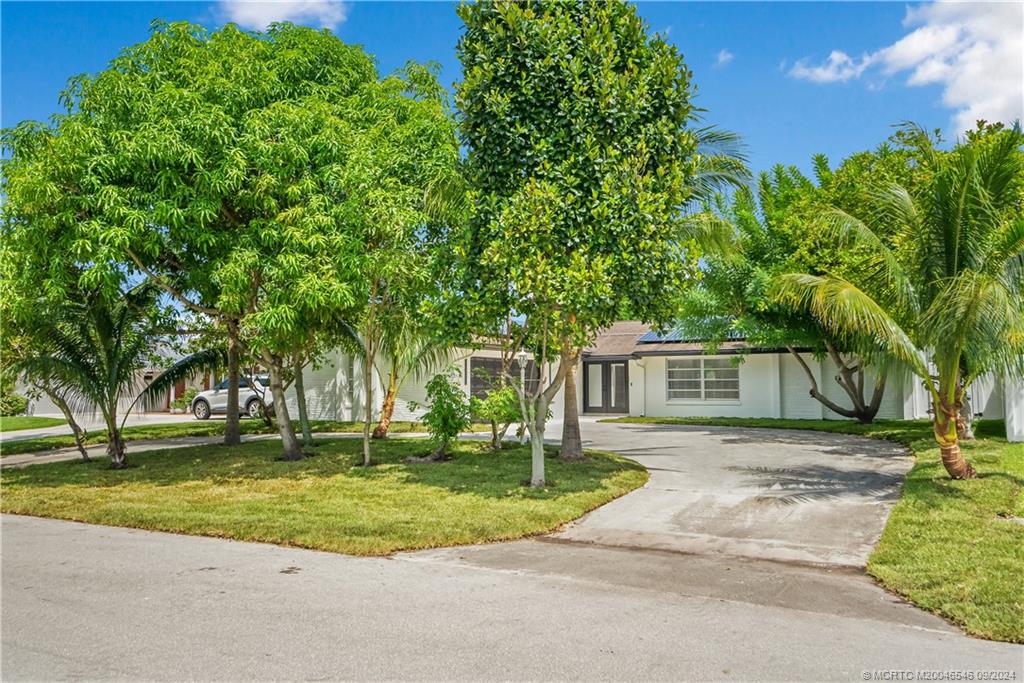 a view of a house with a big yard and large trees