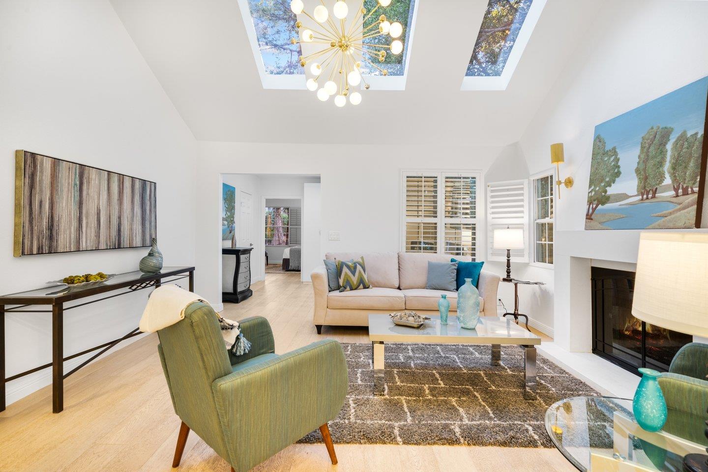 a living room with furniture a fireplace a chandelier and windows