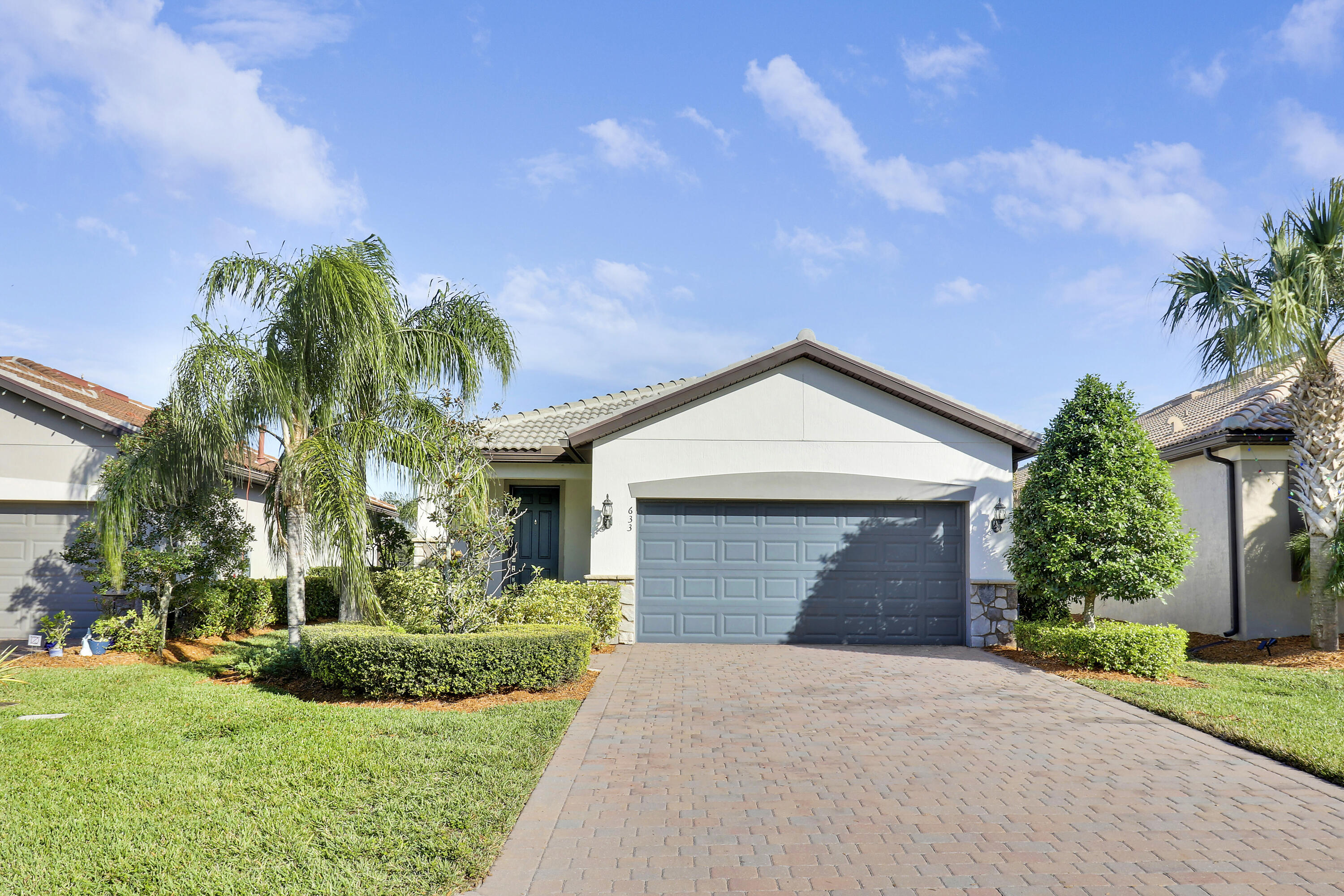 a front view of a house with a yard and potted plants