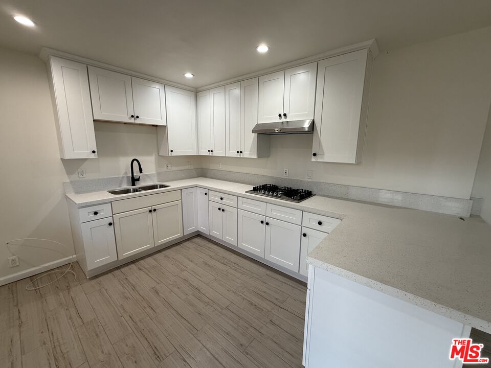 a large kitchen with cabinets wooden floor and stainless steel appliances