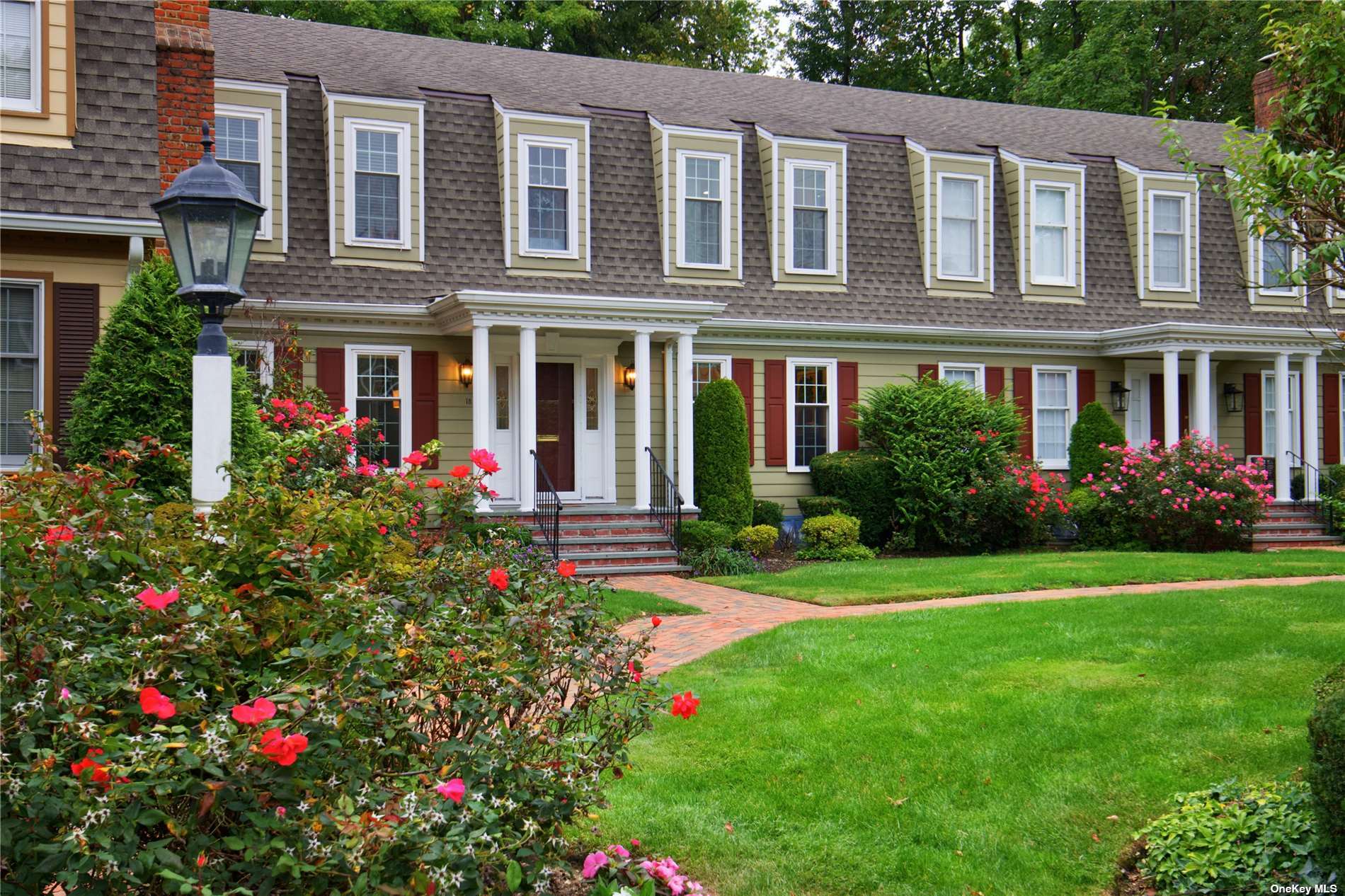 a view of a house with many windows and flower garden