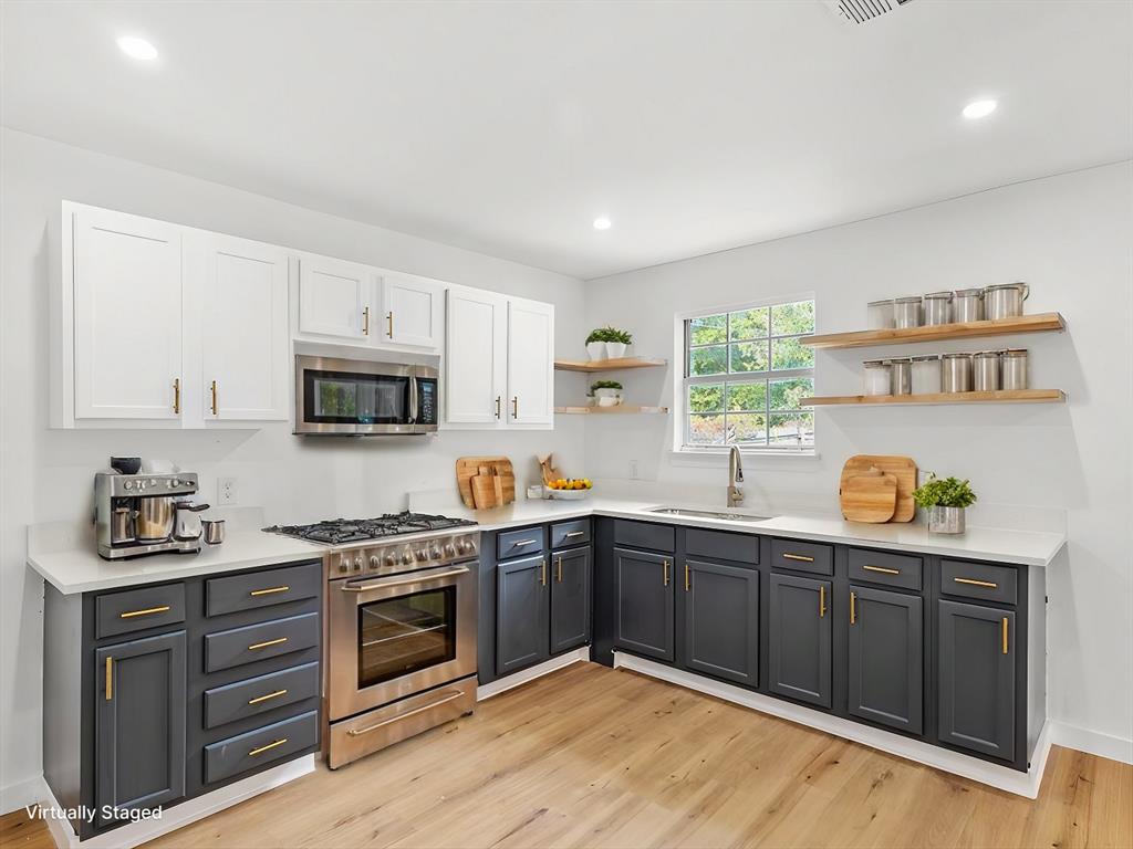 a kitchen with stainless steel appliances granite countertop a stove a sink dishwasher and a microwave with wooden cabinets